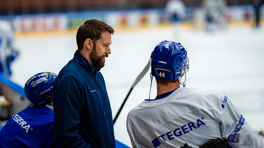 Jesper Gillerås står vid ishockeyrinken med spelare. 